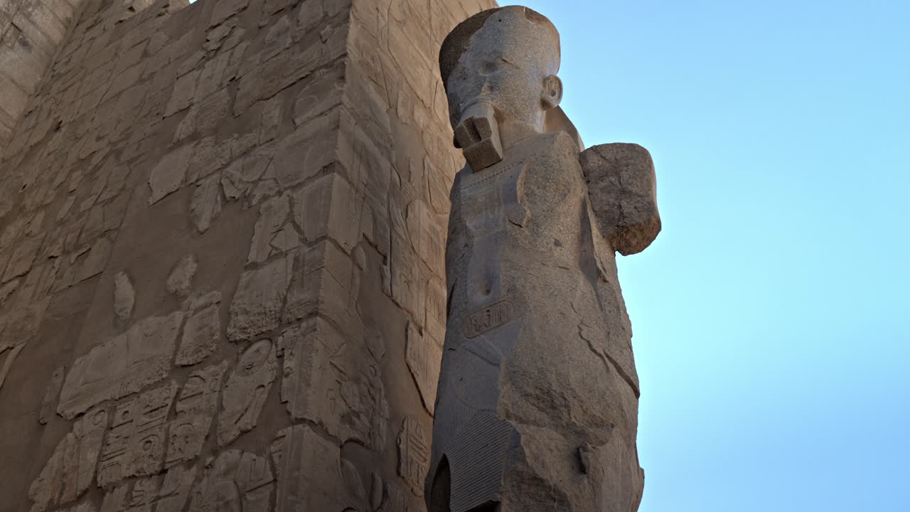 Klippi, joka on kuvattu Egyptin Luxorin Karnakin temppelikompleksissa, näyttää valtavan pystyssä seisovan faaraon patsaan nojaamassa massiiviseen, hieroglyfeillä peitettyyn pyloniin.