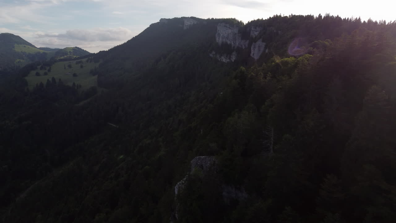 Slow rotating aerial shot of cliffs in the countryside of Sainte Croix, Switzerland with sun rays in frame.