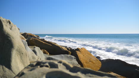 Una-Ola-Oceánica-Chocando-Y-En-Cámara-Lenta-Contra-Una-Playa-Rocosa-De-California-Se-Desliza-Hacia-La-Derecha