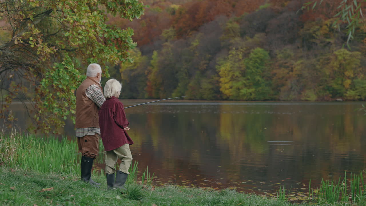 Grandfather and Grandson Fishing by a Lake in Autumn