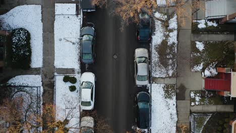 Antena,-Filas-De-Autos-Estacionados-En-Una-Calle-Residencial-Con-Nieve-Invernal,-De-Arriba-Hacia-Abajo