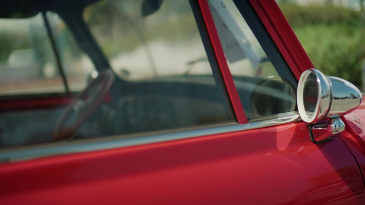Close-up de retrovisor de carro clássico vermelho vintage e carroceria brilhante com profundidade de campo rasa e reflexos suaves da luz do sol