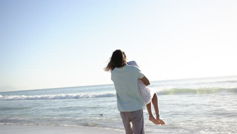 biracial couple enjoys a playful moment on a sunny beach