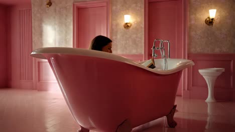 woman reading in a pink bathtub