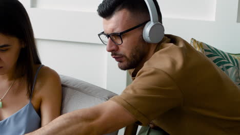 Close-Up-View-Of-A-Student-Talking-With-Female-Mate-Sitting-On-Sofa-While-Looking-At-Laptop