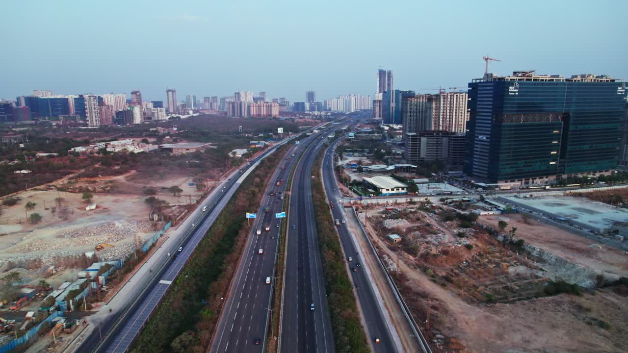 Outer ring road with solar cycle track and buildings at khanapur, financial district, nanakramguda, hyderabad, telangana, india. day time, moving down, tilt up, drone shot, 4k.
