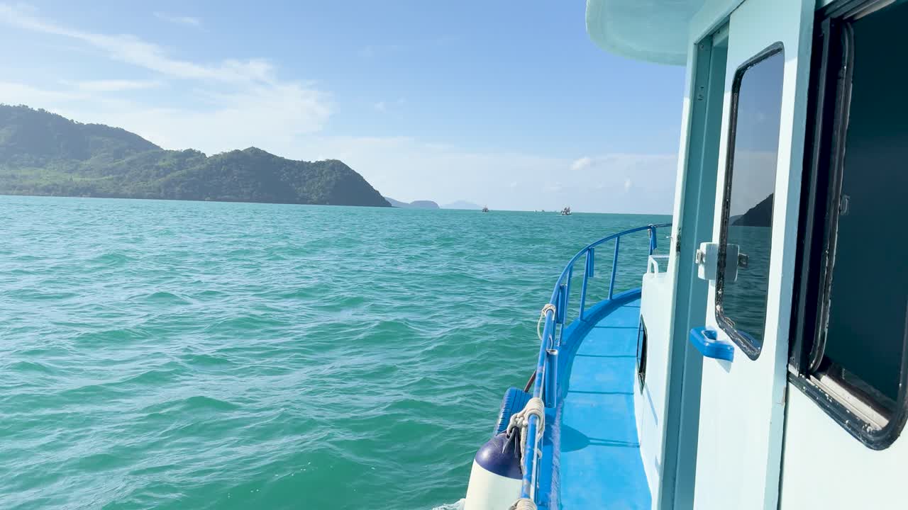 A boat glides through turquoise waters near Ko Racha Yai, under clear skies, capturing the tranquil beauty of Phuket