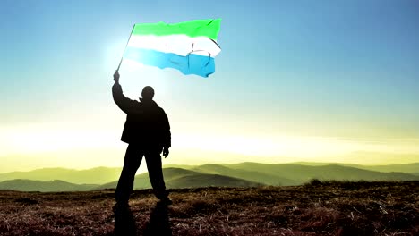 exitoso hombre silueta ganador agitando bandera de sierra leone en la parte superior del pico de la montaña, fondo de bucle cinemagraph