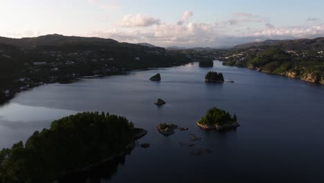 aerial dolly over scattered islands with dense evergreen tree forest with homes built up on either side of the mountains