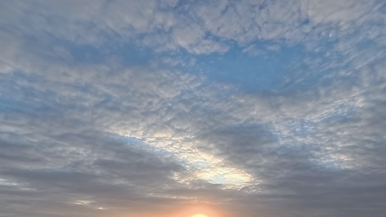 황금빛의 해가 지는 아래로 시간의 흐름이 흐르는 구름이 빠르게 하늘을 가로질러 지나갑니다.