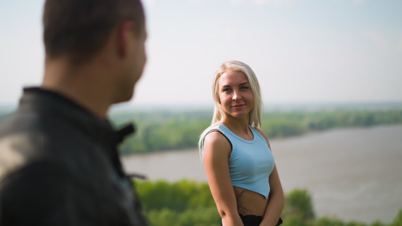 여자 가 돌아서서 은행 에 있는 사랑 하는 남자 모터사이클리스트 에게 미소 짓는다