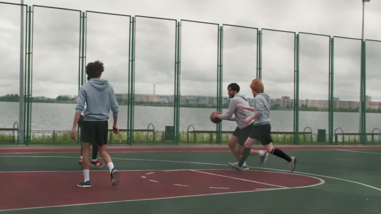 People playing basketball outdoors near a body of water