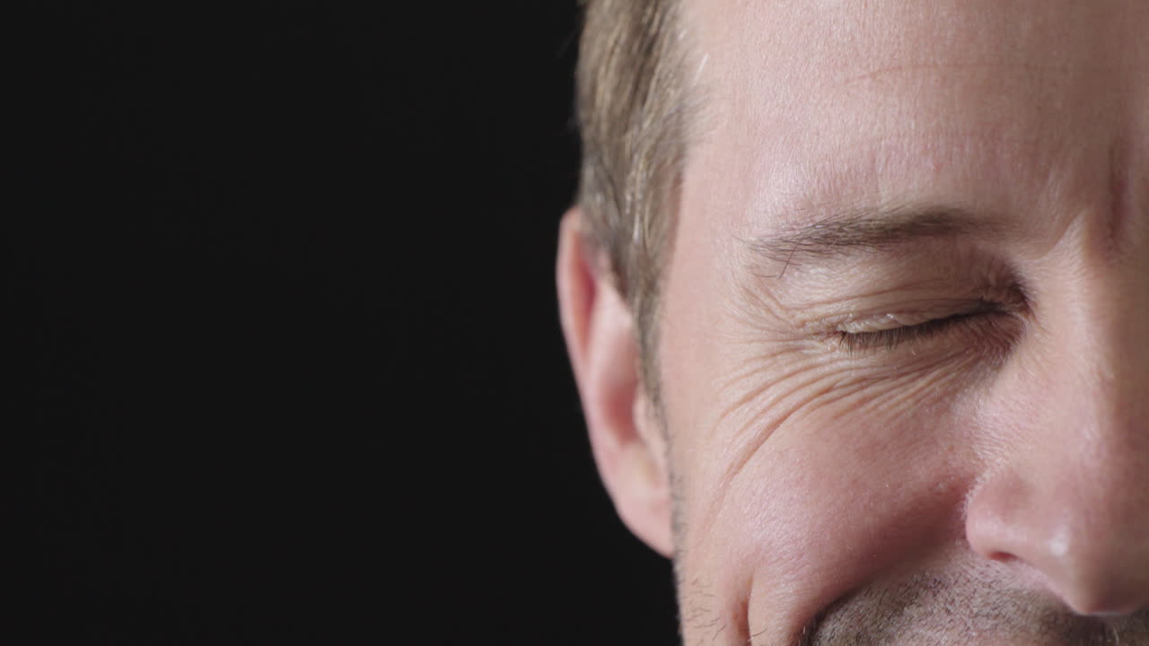 백인 남자의 절반 얼굴 클로즈업 파란 눈 카메라를 보고 웃는 행복 검은 배경 복사 공간에 고립