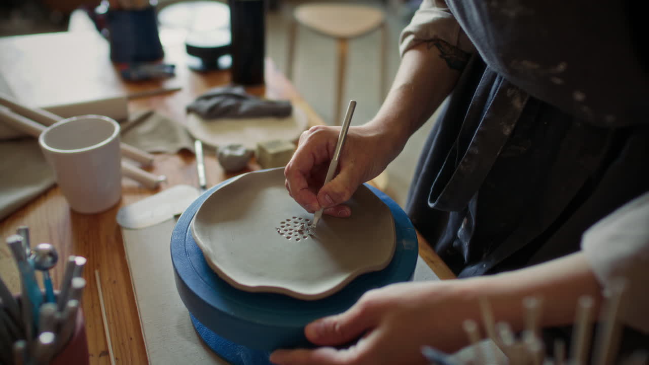 Female Potter Carving Pattern into Clay Plate with Loop Tool on Turntable