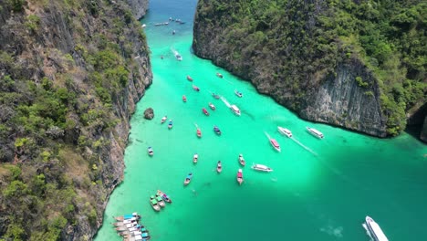 boats in vibrant pileh lagoon of phi phi island on sunny day, aerial