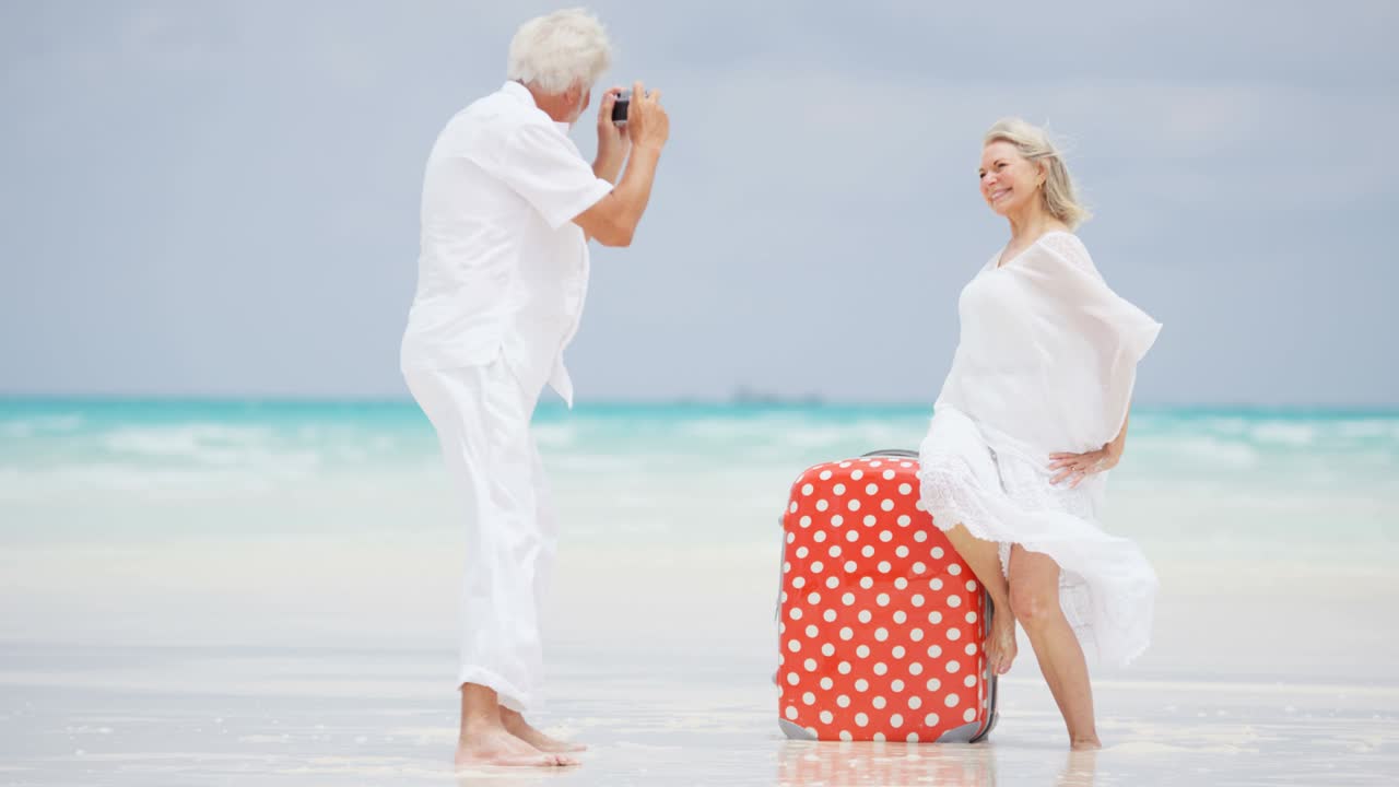 수하물 가방 을 들고 해변 에 있는 백인 여성 노인 들