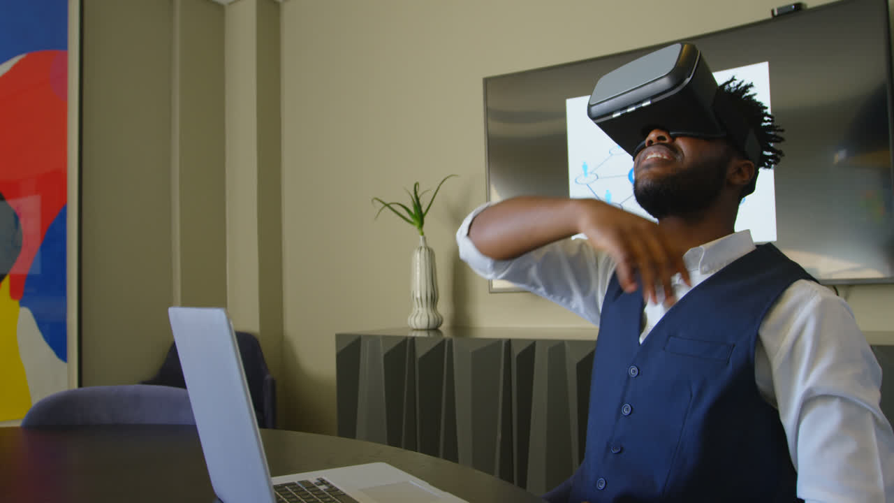 Side view of young black businessman gesturing while using virtual reality headset in office 4k