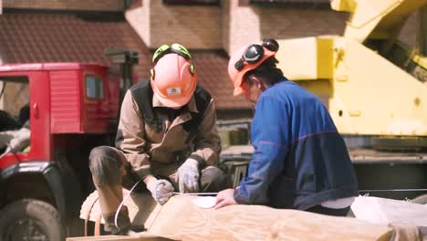 construction workers measuring lumber on a site