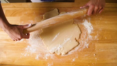 Hands-rolling-dough-with-rolling-pin-on-floured-surface-slow-motion
