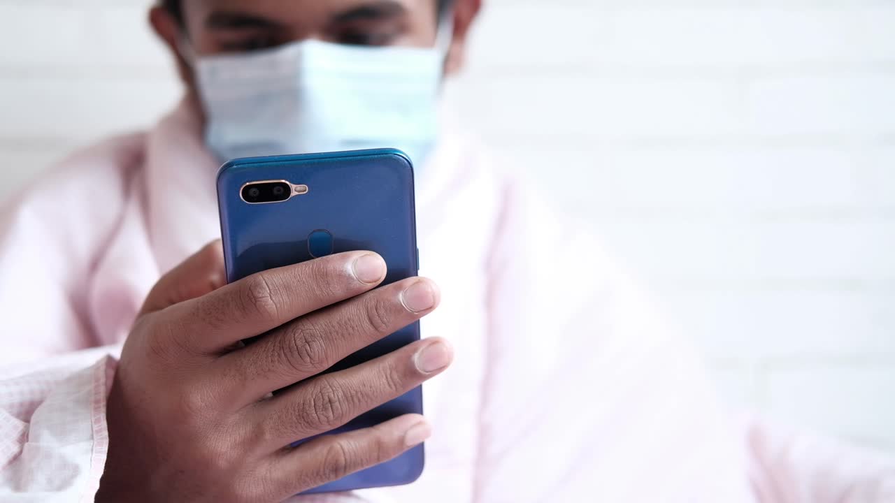 persona que utiliza un teléfono inteligente mientras lleva una máscara