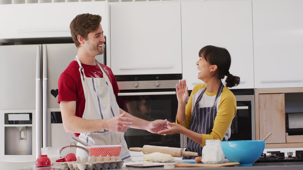 Video di una coppia felice e multietnica che cucina insieme in cucina