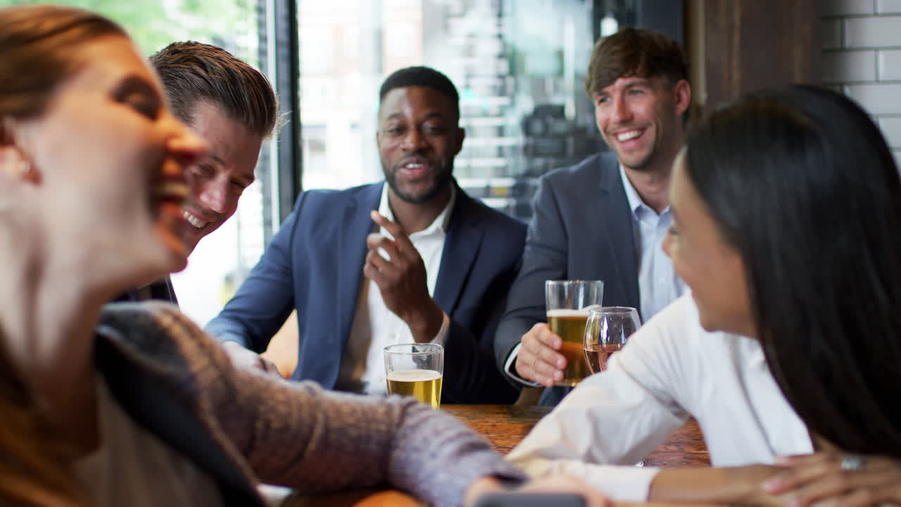 사업 동료 들 이 일 후 술집 에서 휴대전화 에 있는 사진 을 보고 있다