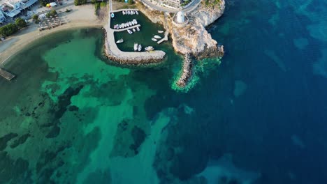 aerial footage of a small little port with a picturesque windmill in the town of parikia, on the island of paros, one of the many cyclades islands in the aegean sea