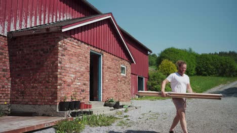 a man is carrying wooden boards came out from a vintage cabin