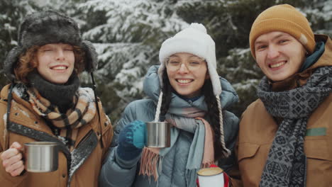 joyful tourists smiling at camera in winter forest