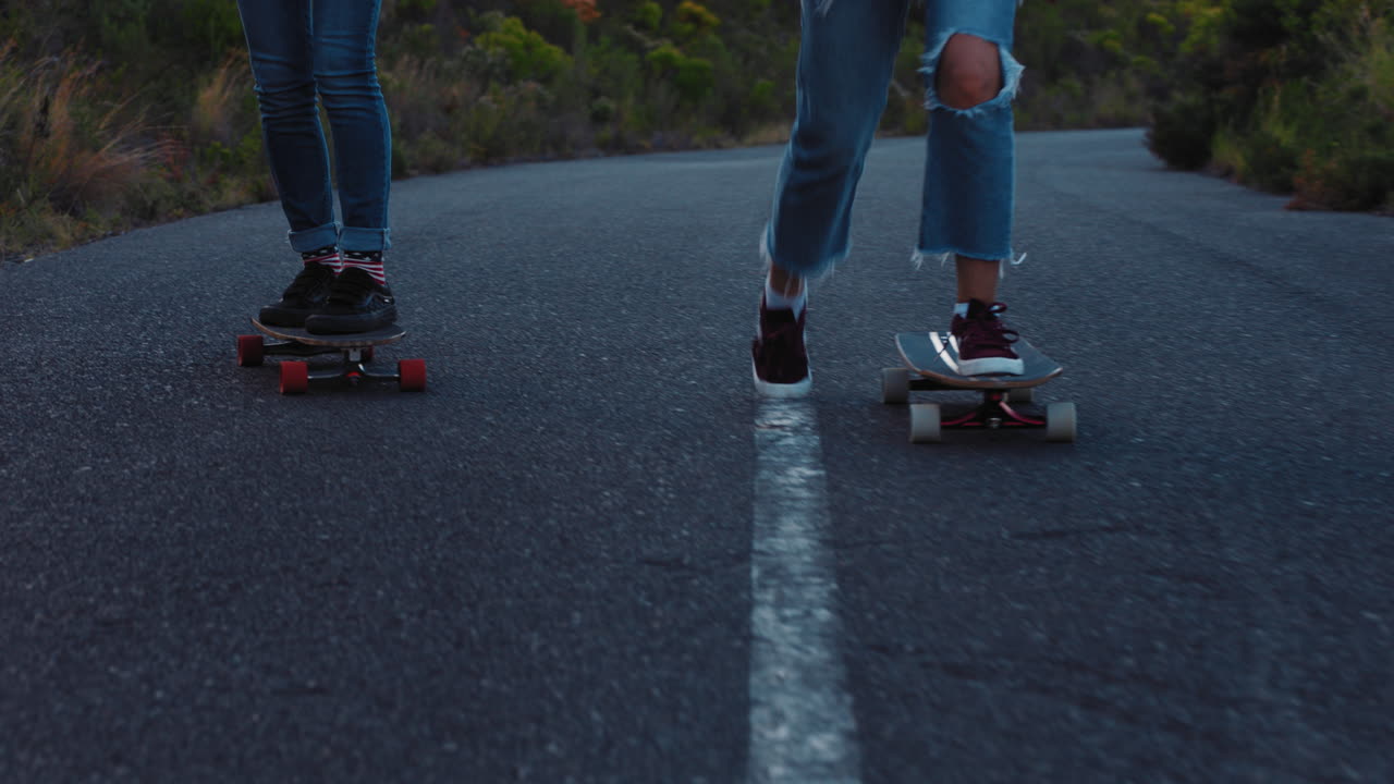 행복한 다민족 친구들이 함께 롱보드를 타고 스케이트보드를 타고 시골 도로에서 즐겁게 놀고 편안한 여름 휴가를 즐기고 있습니다.