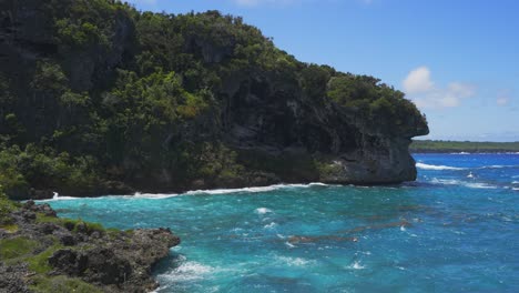 Eine-Tropische-Klippe-Am-Meer-Voller-Vegetation,-An-Der-Tagsüber-Wellen-Krachen