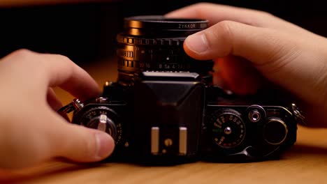 hands adjusting focus, handling, and using a black vintage film camera