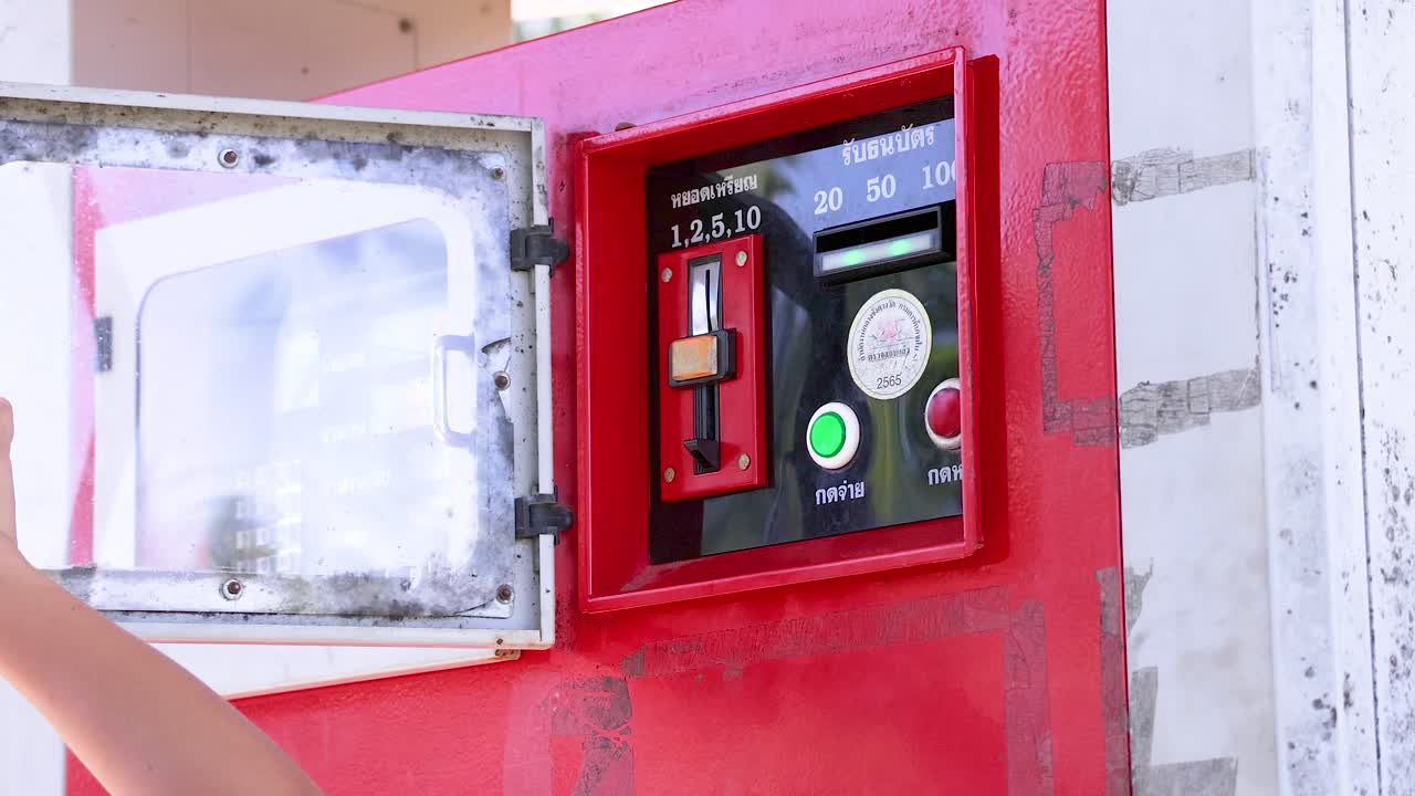 A person operates a coin-operated fuel dispenser in bright daylight at Khao Rang Viewpoint, Phuket, Thailand
