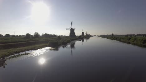 A-drone-shot-panning-backwards,-around-Dutch-Windmills-during-sunrise