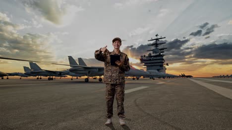 full body of asian man soldier smiling and pointing to a tablet in his hand while standing on aircraft carrier