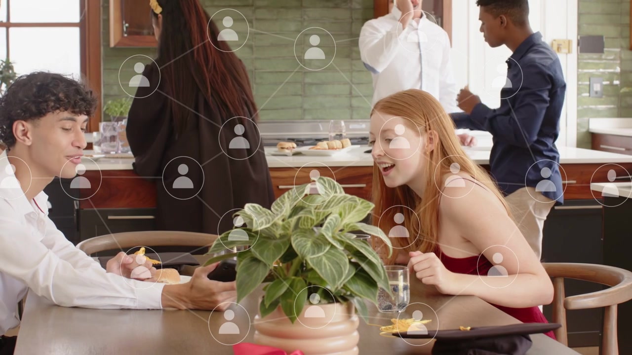 Pareja sentada charlando en la mesa de la cocina, tocando el teléfono y haciendo que iconos de usuario vinculen contactos sociales.