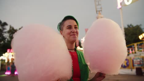 Y-Una-Chica-Lesbiana-Con-Un-Corte-De-Pelo-Corto-De-Color-Verde-Y-Una-Camisa-Verde-Camina-Con-Una-Parka-Y-Lleva-Dos-Enormes-Algodones-De-Azúcar-De-Color-Rosa-En-Sus-Manos.