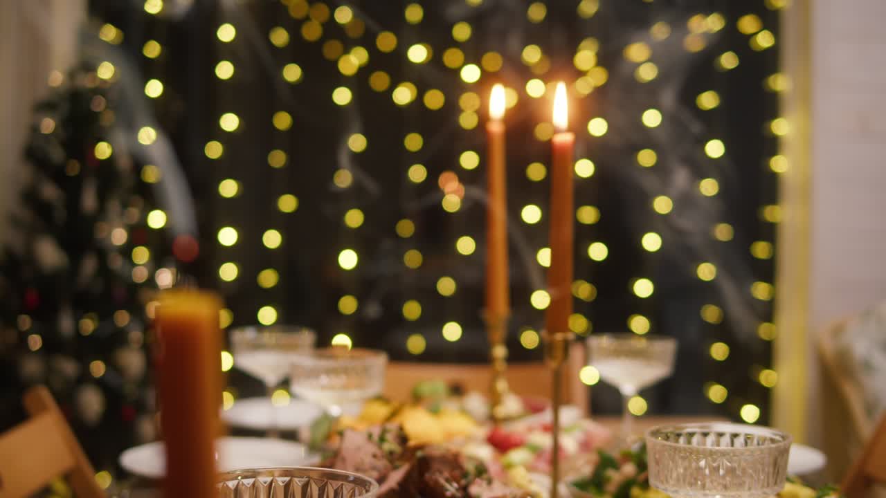 soplar velas en la mesa de comedor de cerca. amigos celebrando el año nuevo, platos deliciosos, comida casera cocinada en platos. fiesta de navidad, cena festiva en casa.