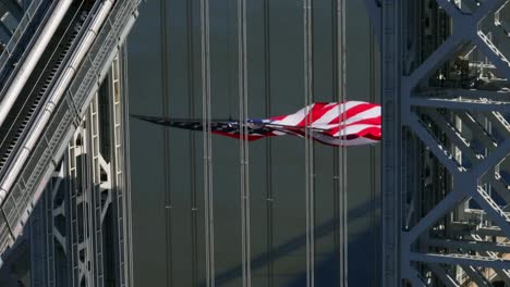 Una-Vista-Aérea-De-La-Torre-En-El-Lado-De-Nueva-Jersey-Del-Puente-George-Washington-Con-Una-Enorme-Bandera-Estadounidense-Ondeando-En-Un-Día-Soleado