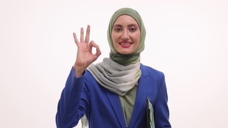 smiling muslim woman in hijab making an 'ok' gesture