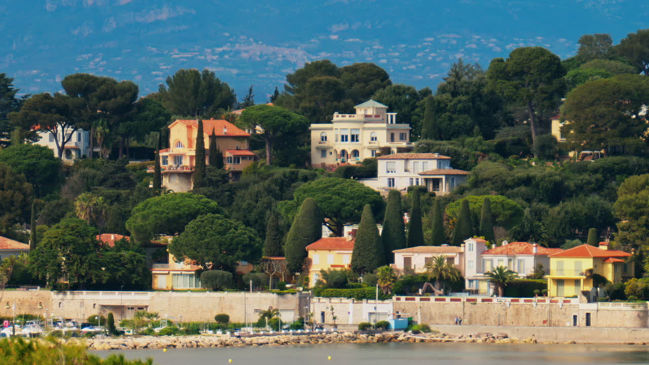 Distant view of multiple villas surrounded by green trees with the mountains on the background