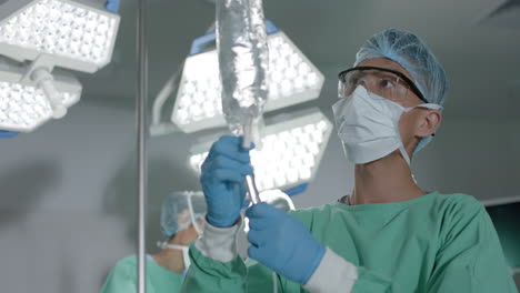 un joven asiático con trajes médicos prepara una bolsa intravenosa en un hospital.