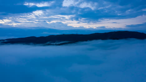 tomada de avión no tripulado de nubes de inversión en movimiento justo debajo de las montañas