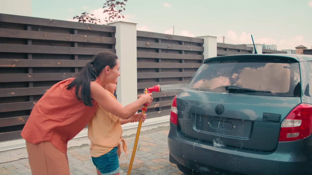 Mother And Daughter Washing Car Together