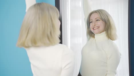 Happy-and-cheerful-young-woman-looking-at-herself-in-the-mirror.