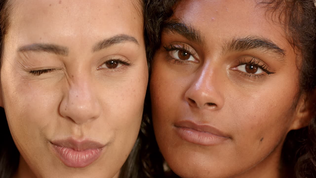 Close-up of two multiracial female friends making playful faces, celebrating friendship, at home