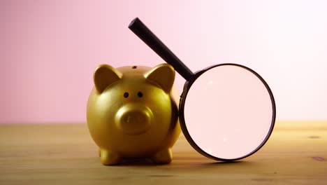 piggybank with magnifying glass on the wooden table