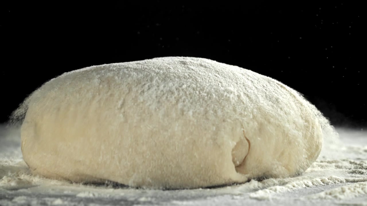Fresh Dough Ball Falling onto Floured Surface in Slow Motion