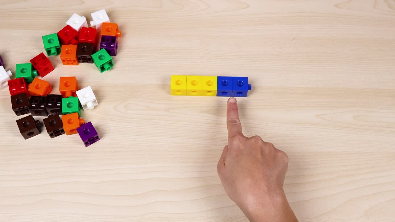 손은 테이블 위에 있는 다채로운 연결 큐브와 상호 작용합니다.