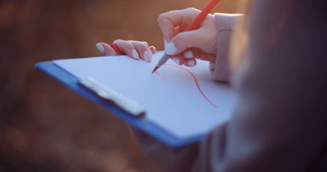 woman drawing heart symbol at clipboard 1